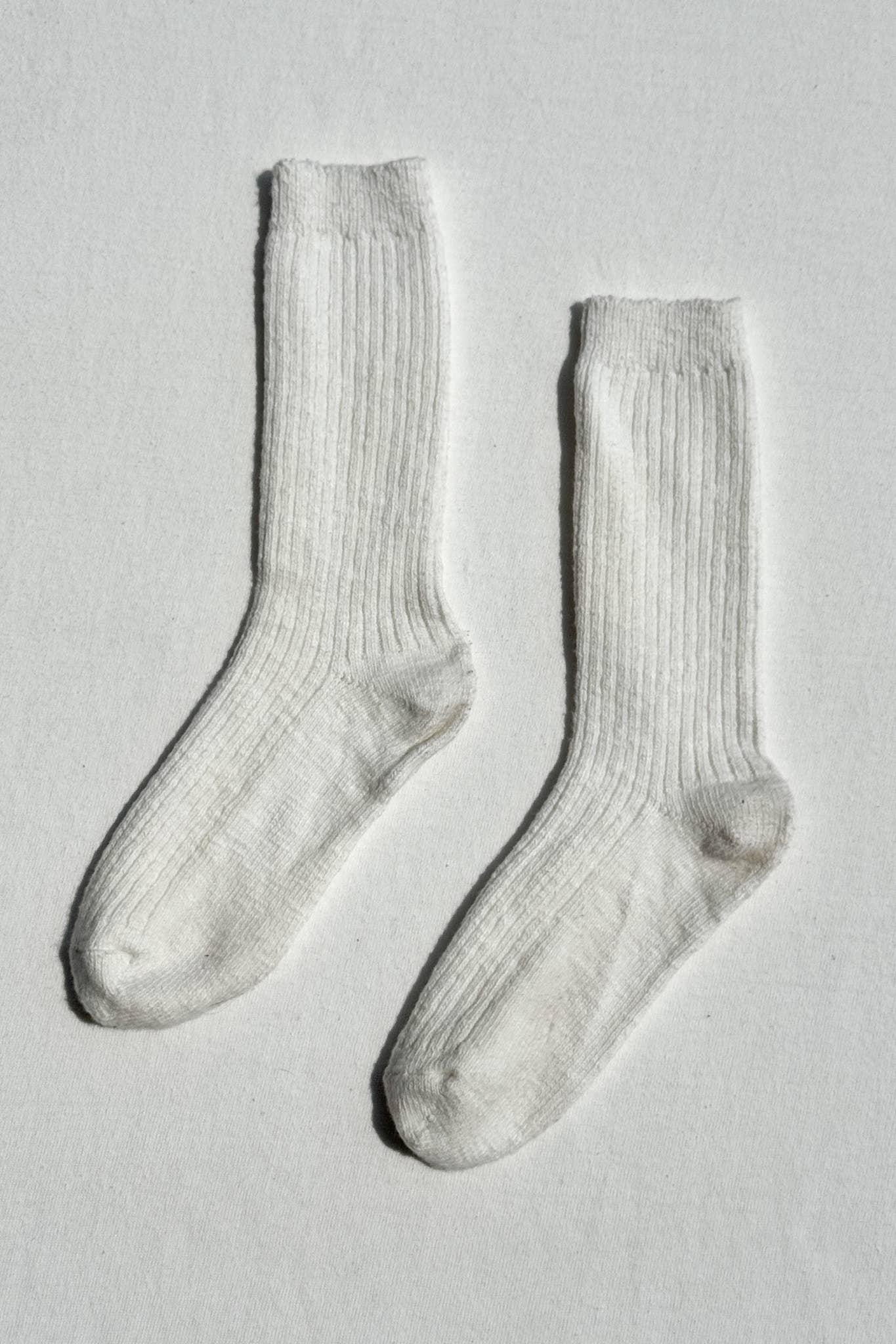 Pair of white Le Bon Shoppe socks on a light grey background