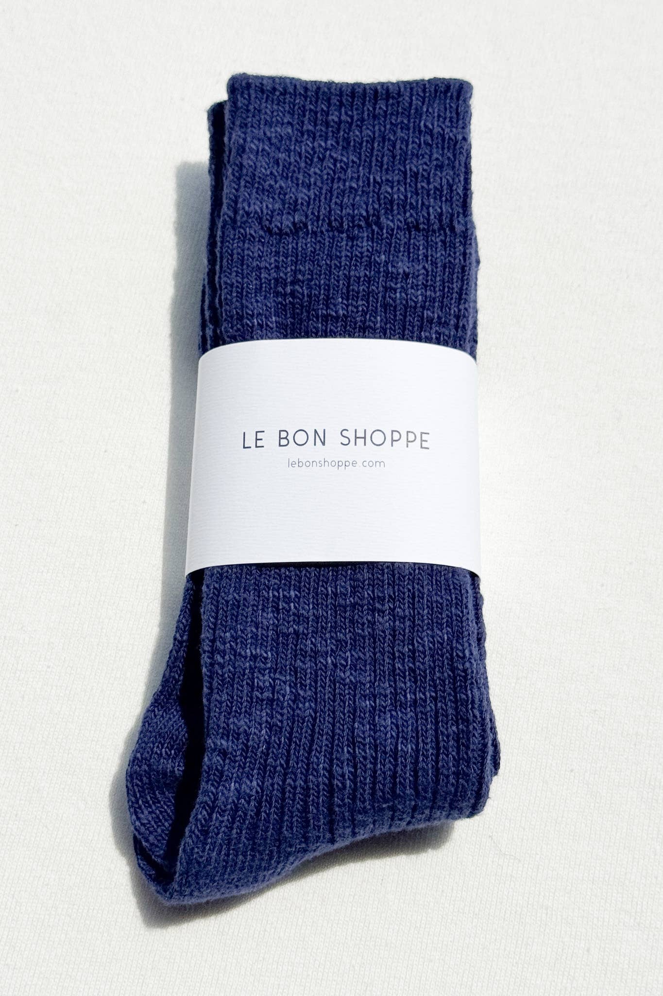 Pair of blue Le Bon Shoppe socks with a white label on a light grey background