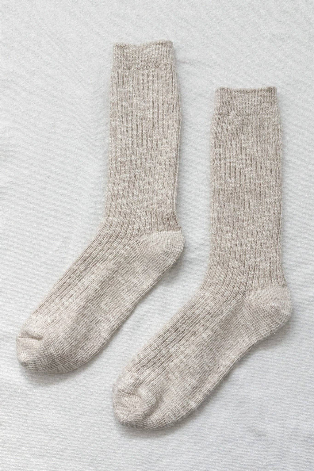 Pair of beige Le Bon Shoppe socks on a light grey background
