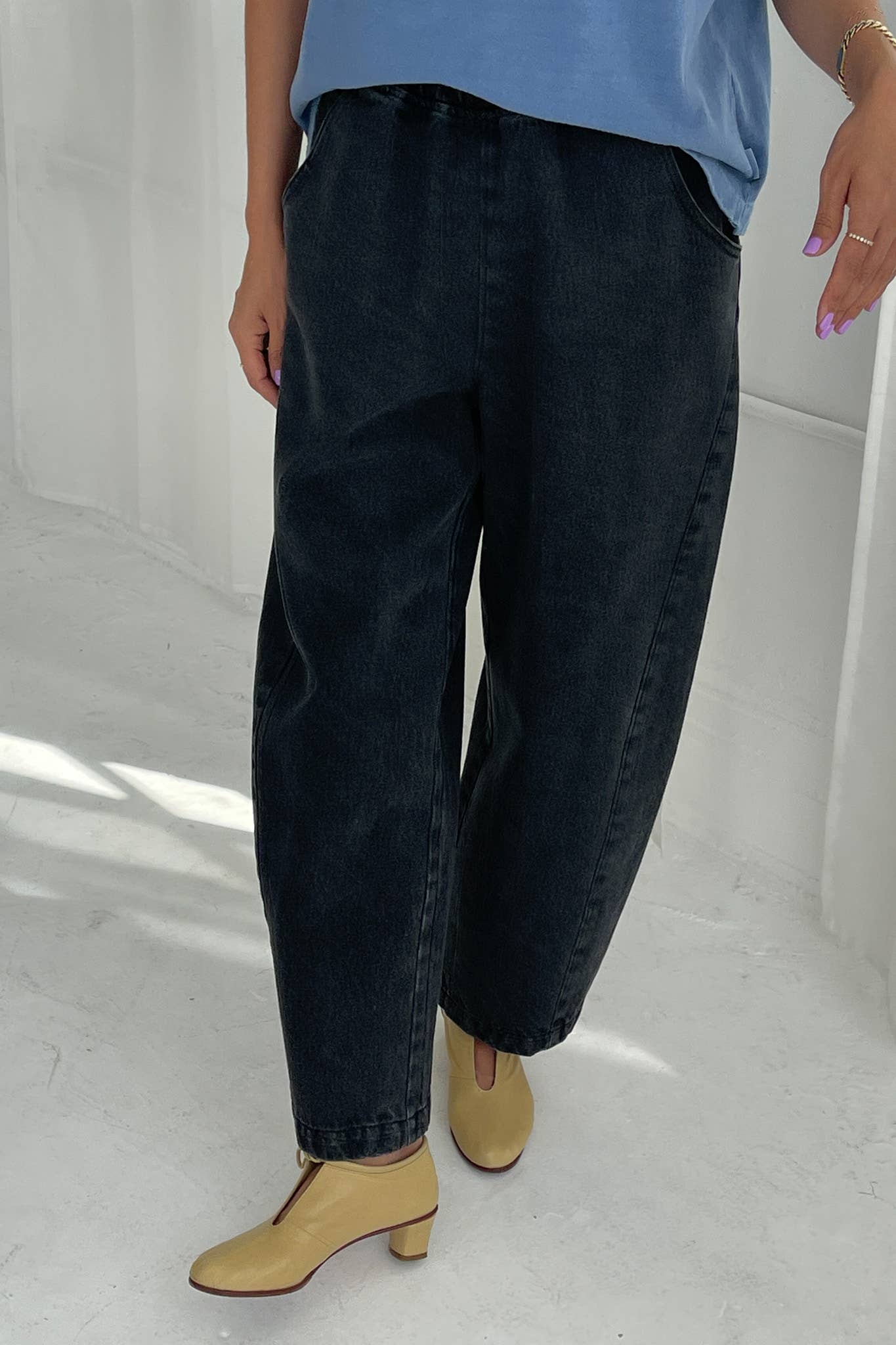 Person wearing black jeans and a blue top on a white background