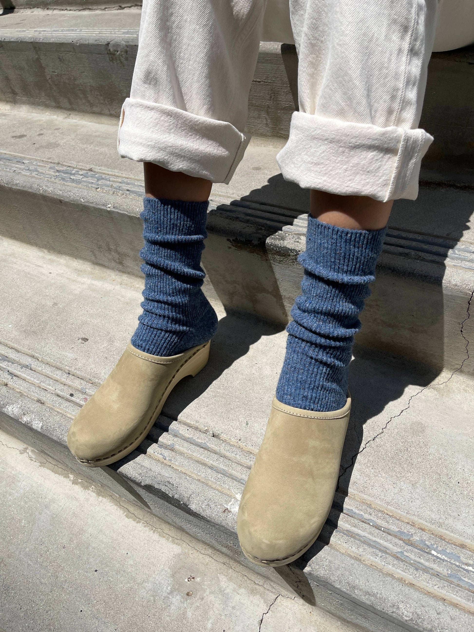 Person wearing blue Le Bon Shoppe socks and beige shoes on a concrete step.