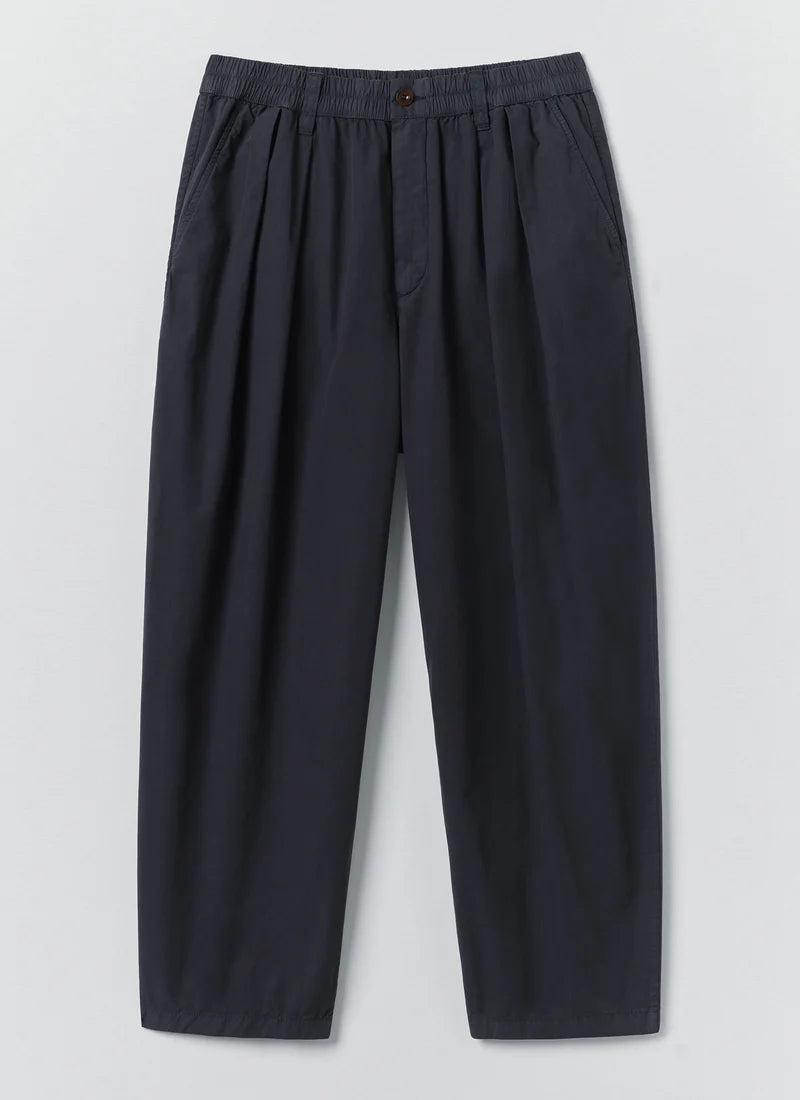 Dark navy blue Toast Casper pleated trousers with an elastic waistband, shown flat on a light grey background.