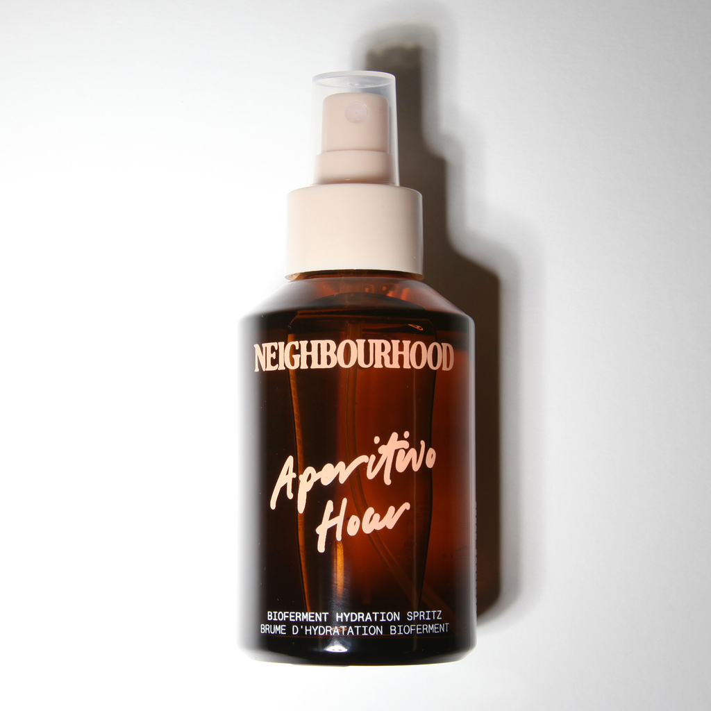 Brown spray bottle labeled 'Neighbourhood Aperitivo Hour' on a white background