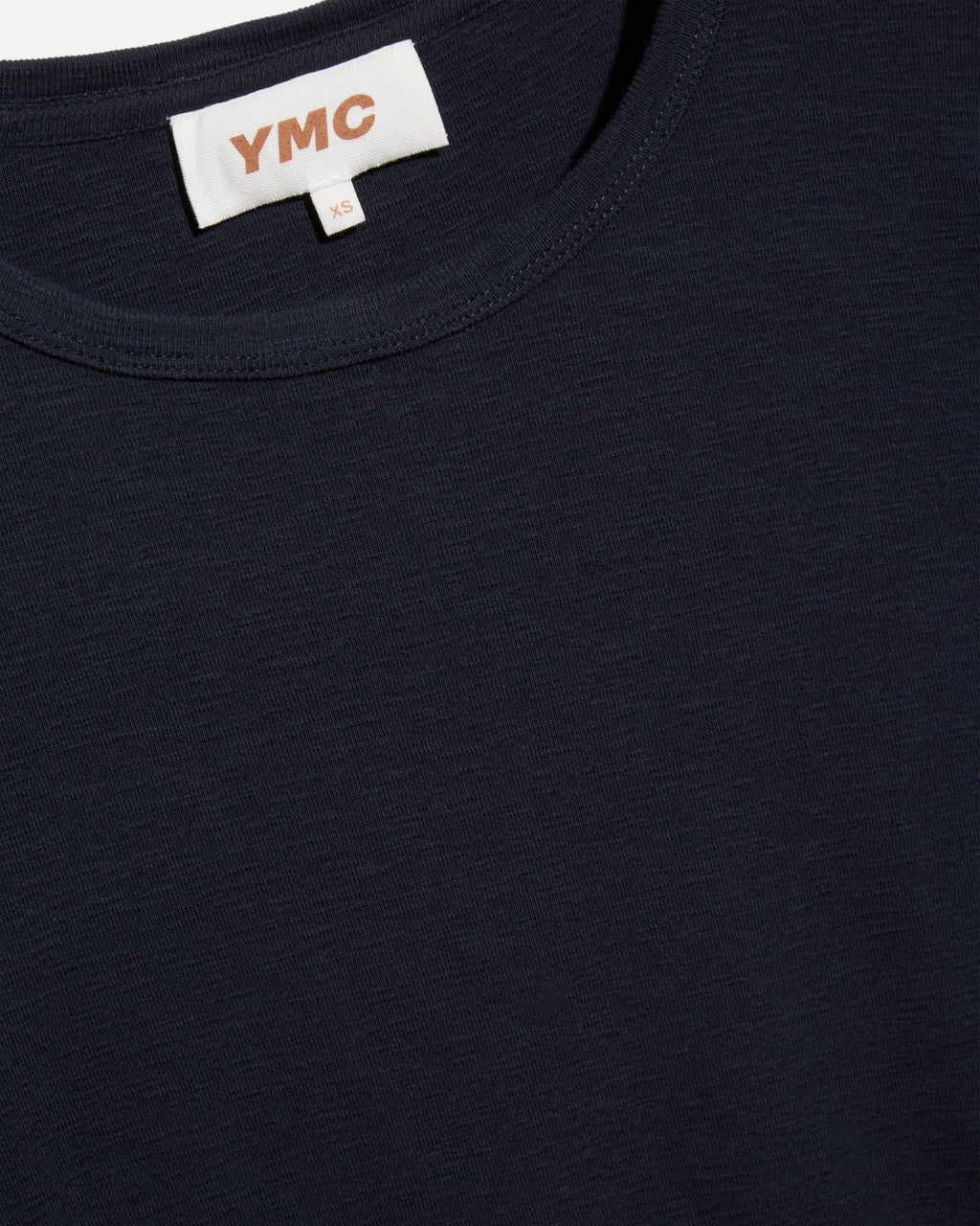 Navy blue t-shirt with a white label displaying 'YMC' on a black background
