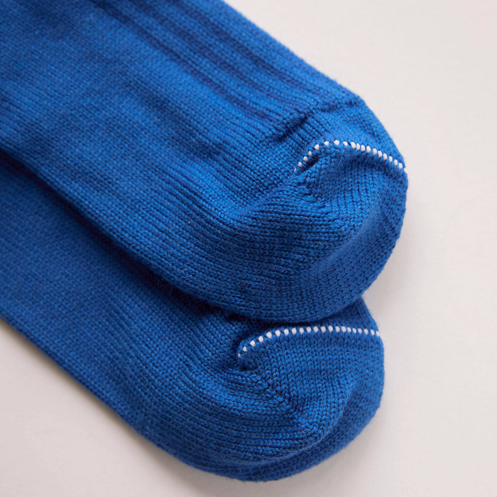 Pair of blue socks with white trim on a light gray background