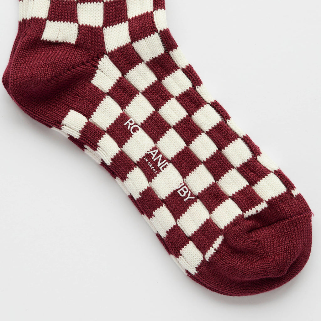 Maroon and white checkered socks with 'Rock and Ruby" branding on a light gray background