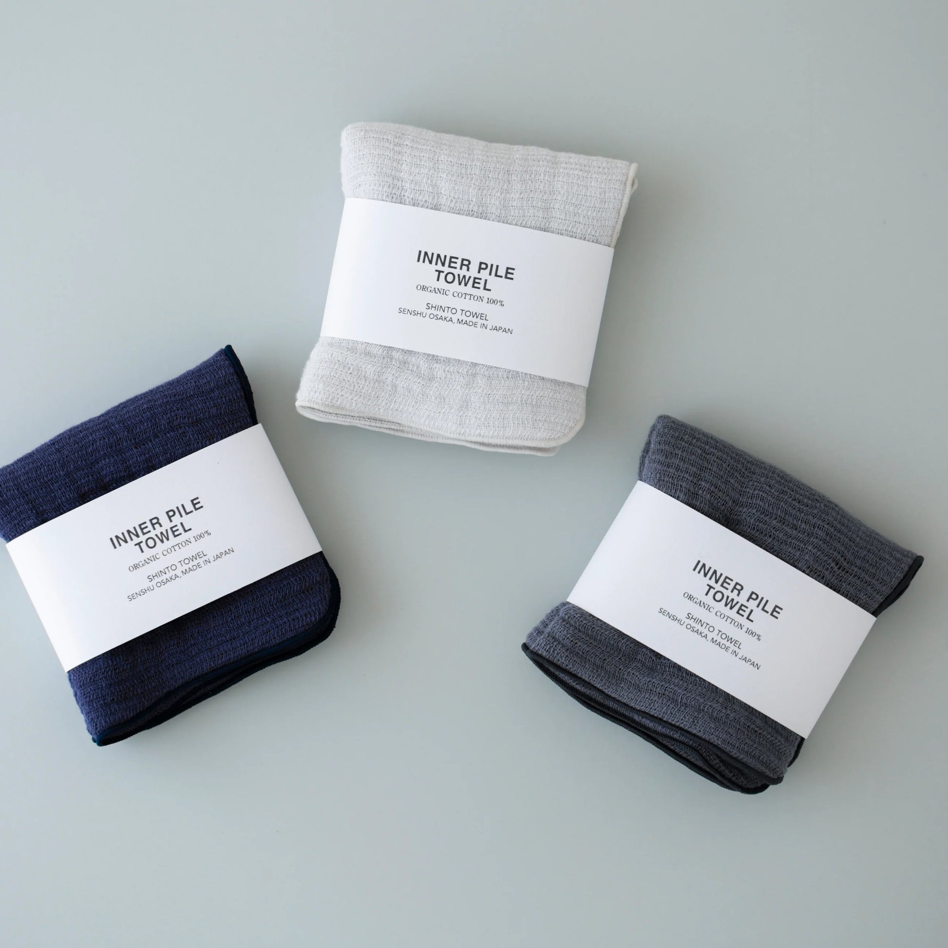 Three folded towels in different colors with labels on a light gray background