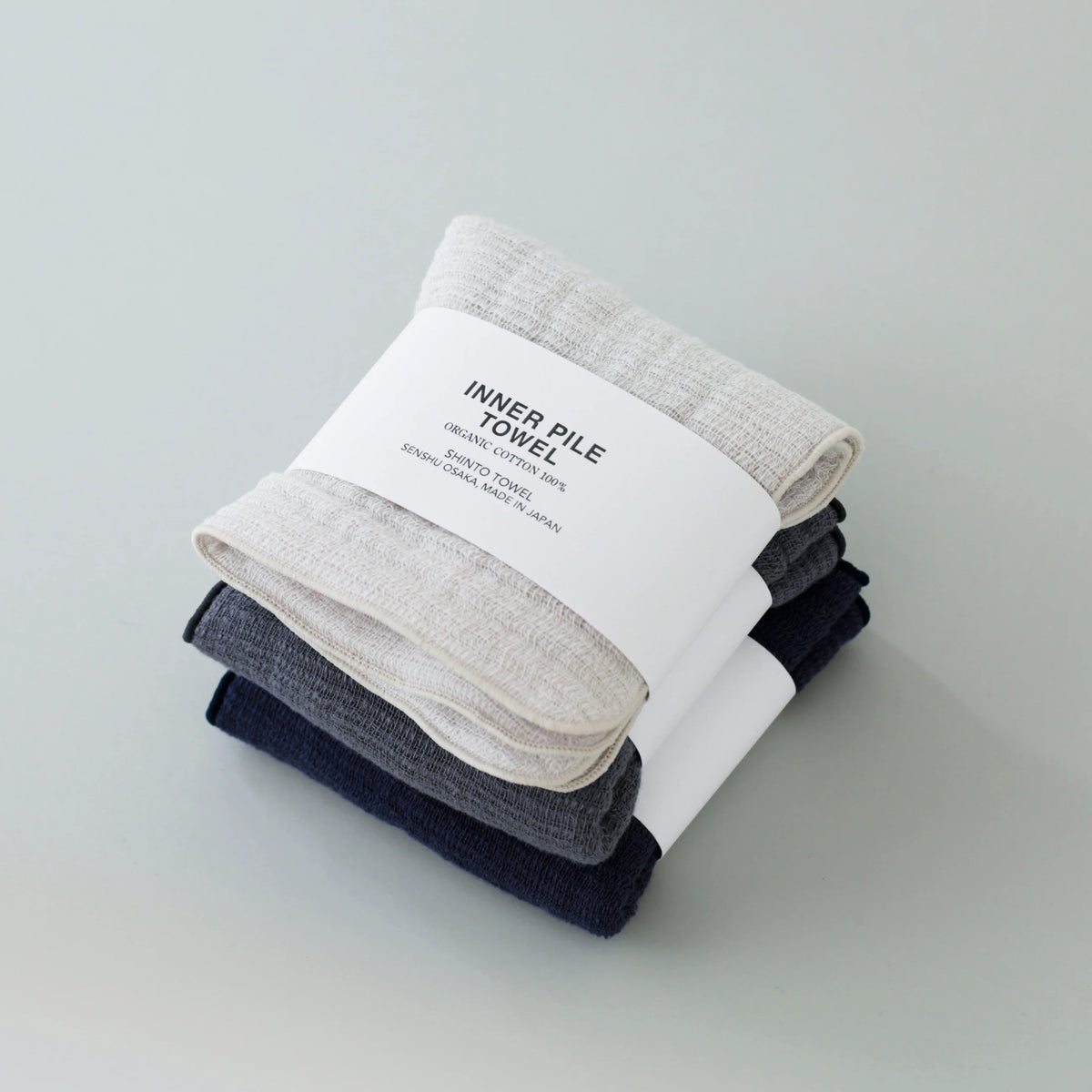 Three folded Inner Pile face clothes on a light grey background 
