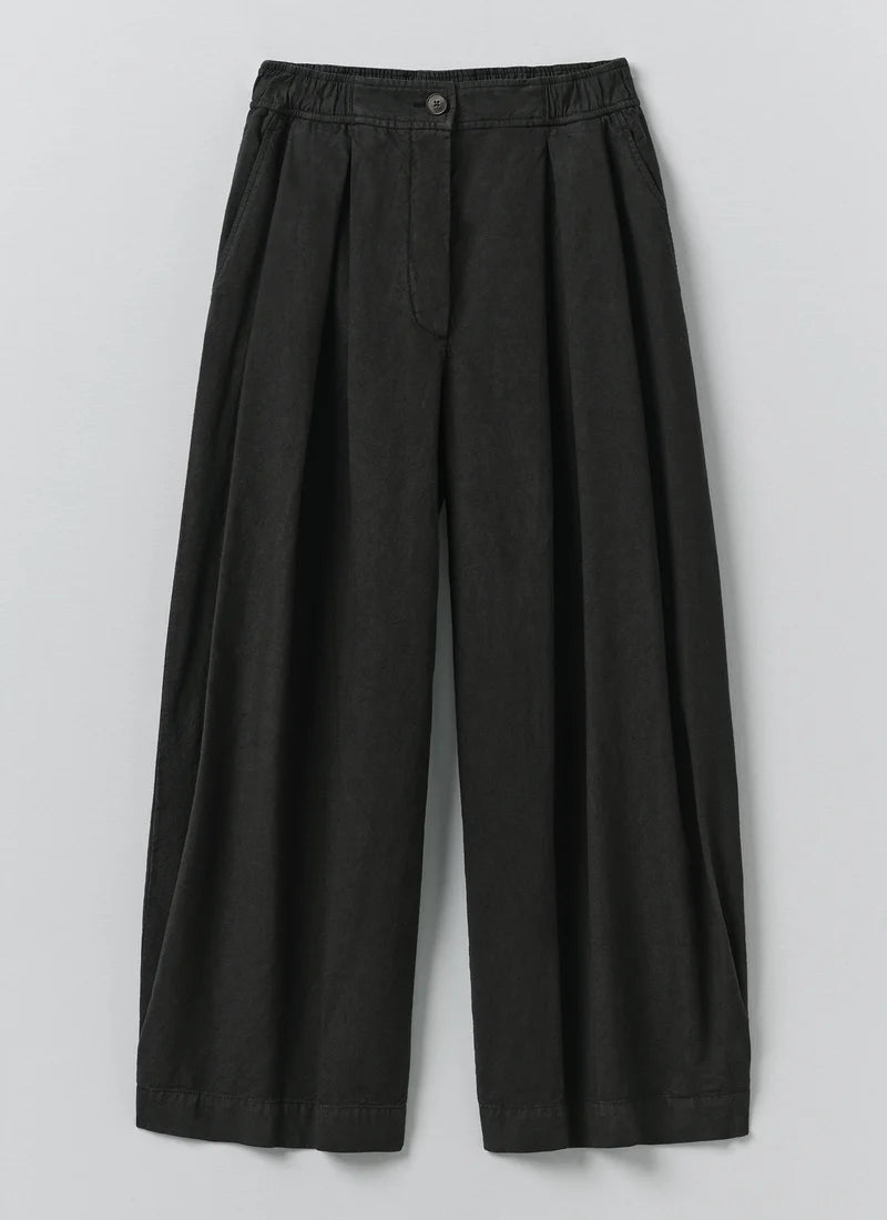 Soft Black Toast wide leg trousers on a light grey background 