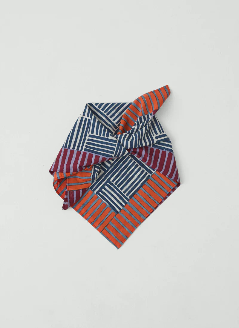 Striped fabric scarf with red and blue pattern on a light gray background