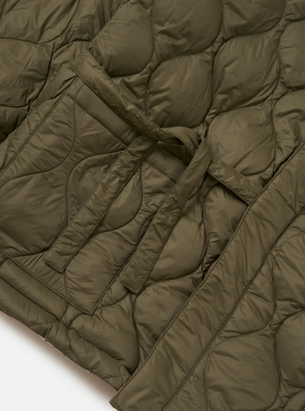Close-up of a quilted olive green jacket on a white background
