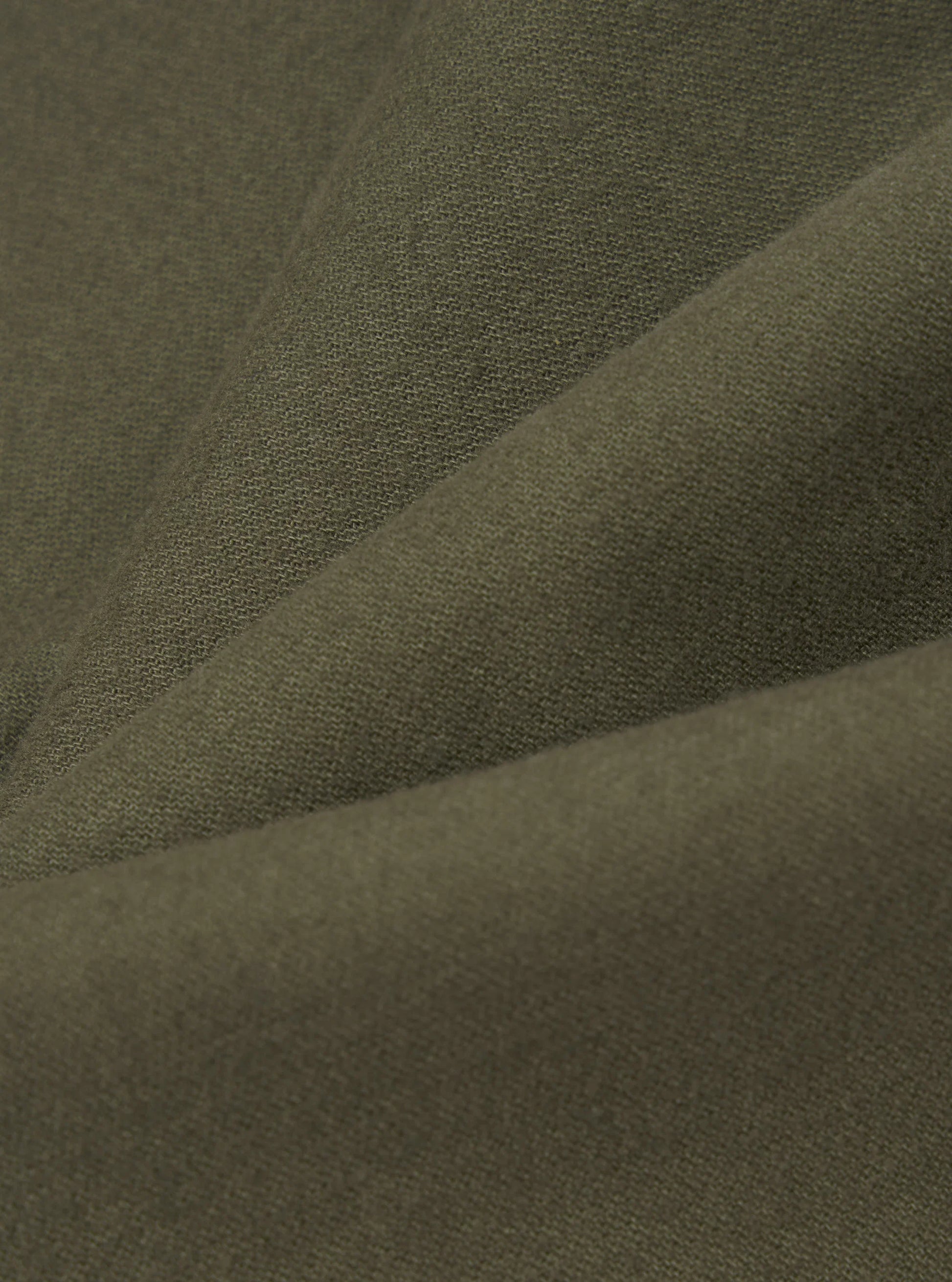 A close-up of draped olive green moleakin fabric with a fine woven texture.
