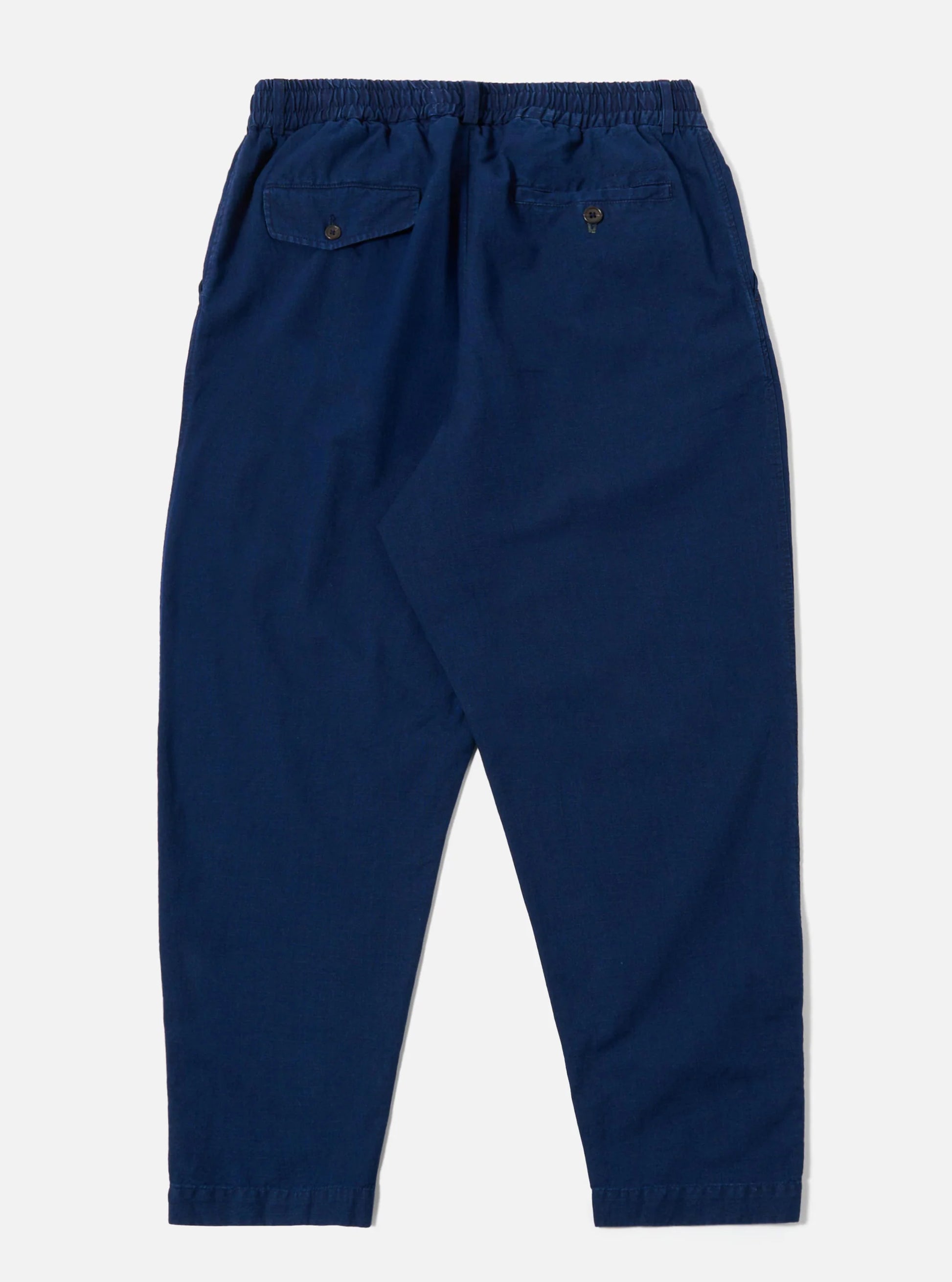 Back view of the Universal Works Indigo pleated track pant against a light grey background.