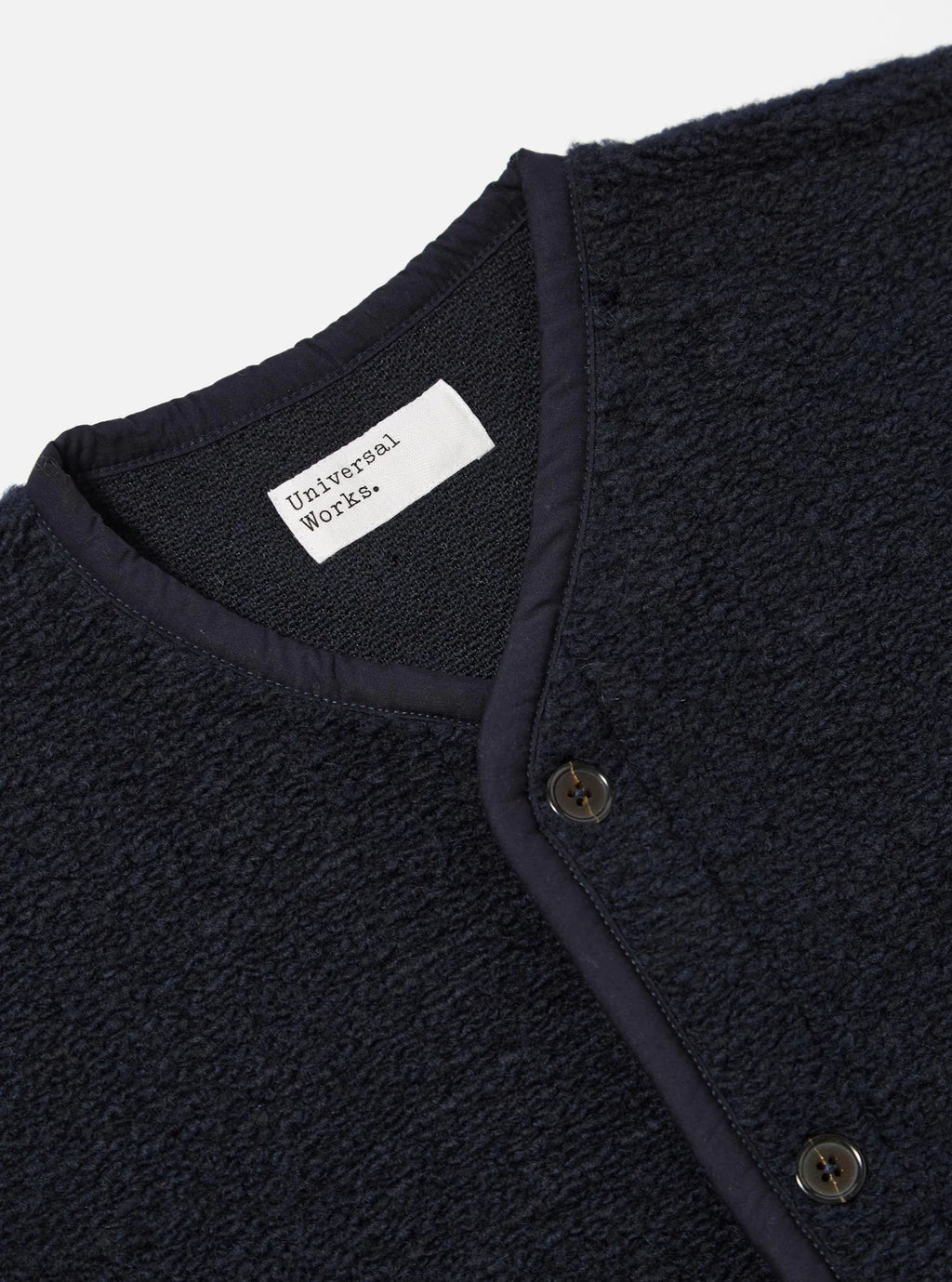 Navy textured Universal Works navy gilet with a visible brand label on a light gray background