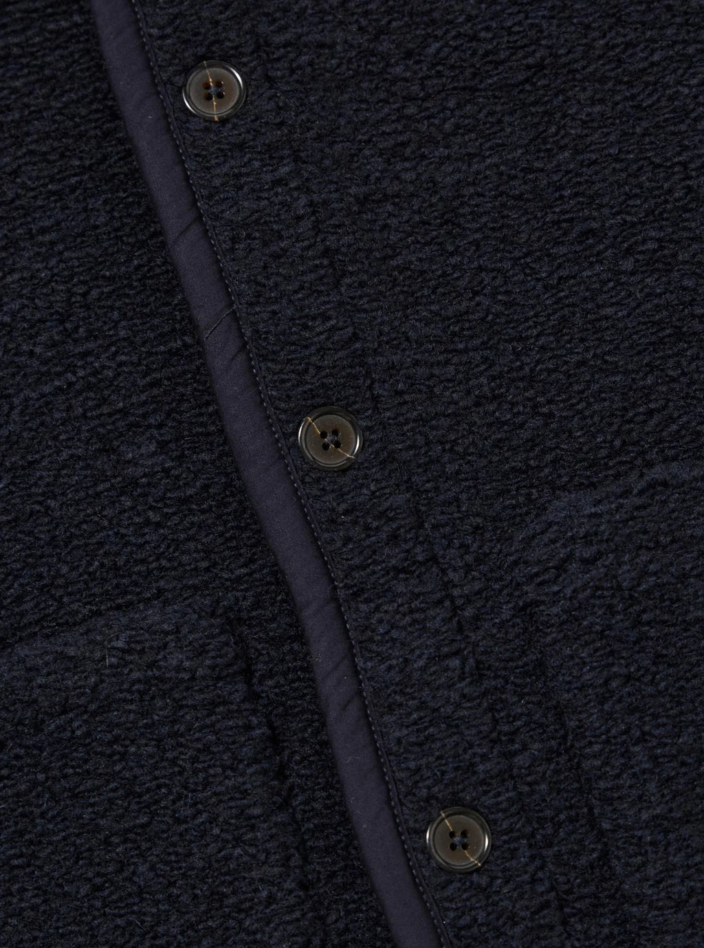 Close-up of a textured Universal Works navy wool fleece with buttons and a seam.