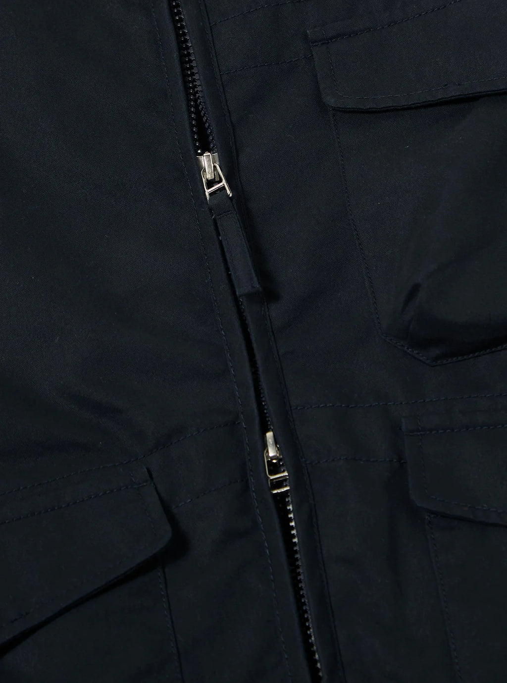 Close-up of a Universal Works navy jacket with a zipper