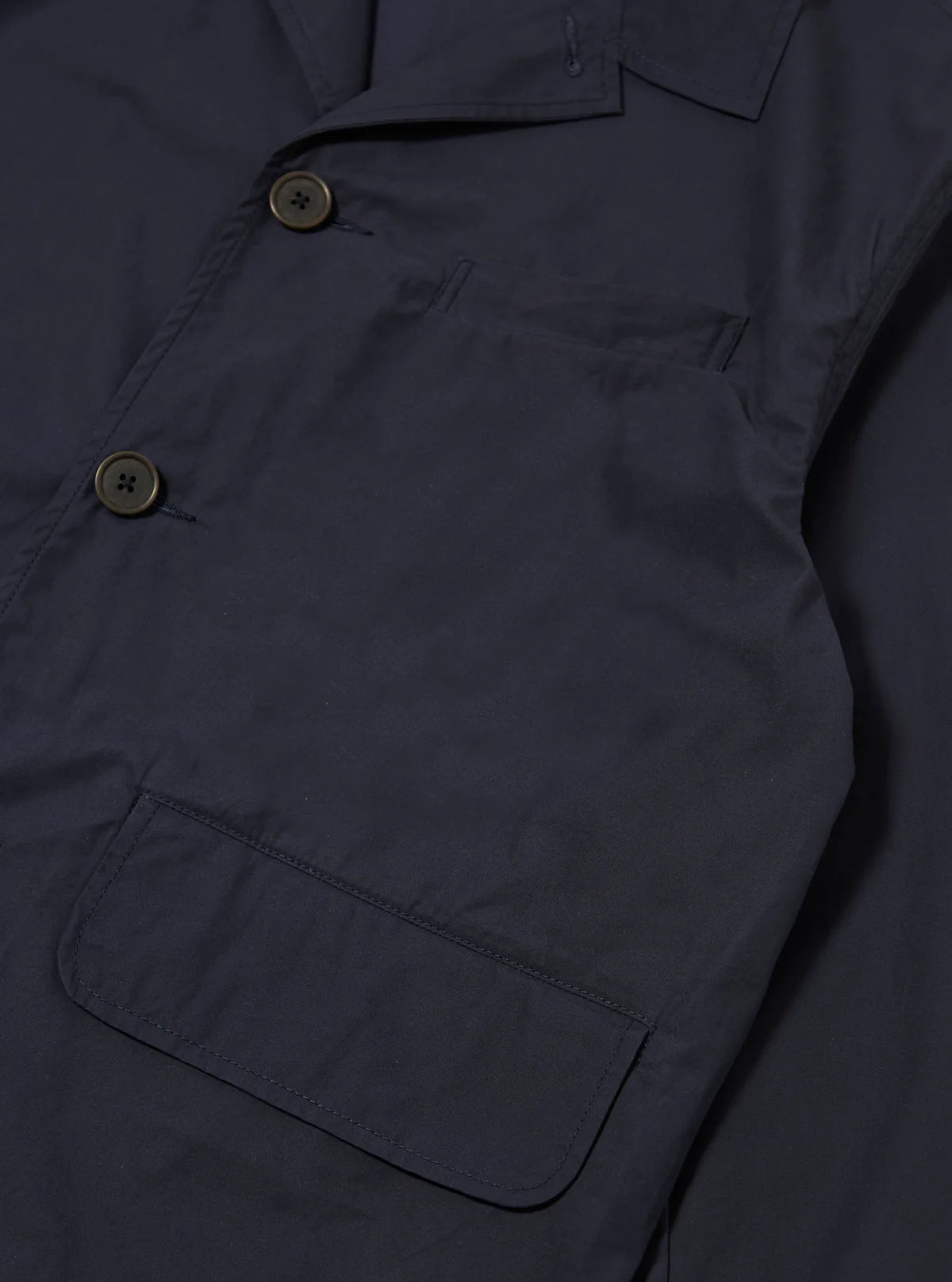 Navy jacket with button details on a dark background