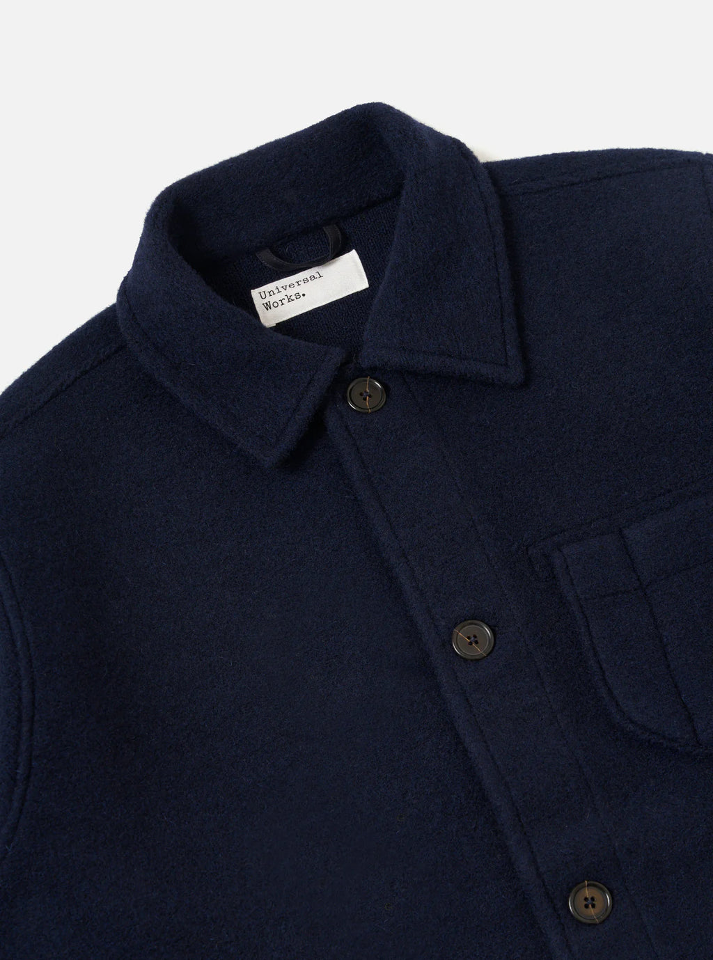 Universal Works navy blue coat with a collar and buttons, featuring a brand label on a light grey background.