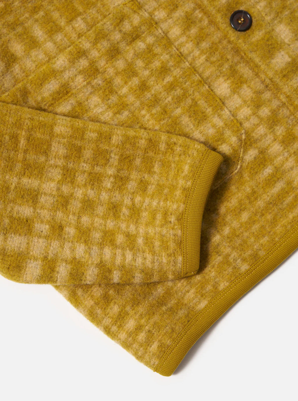 Close-up of a Universal Works mustard yellow textured cardigan with a check pattern on a white background