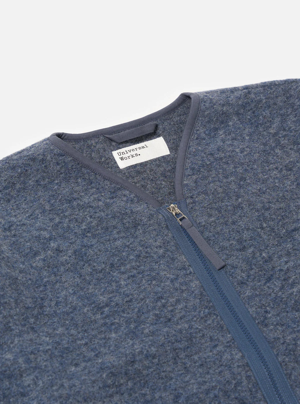 Blue fleece jacket with a zipper and 'Universal Works' label on a light gray background