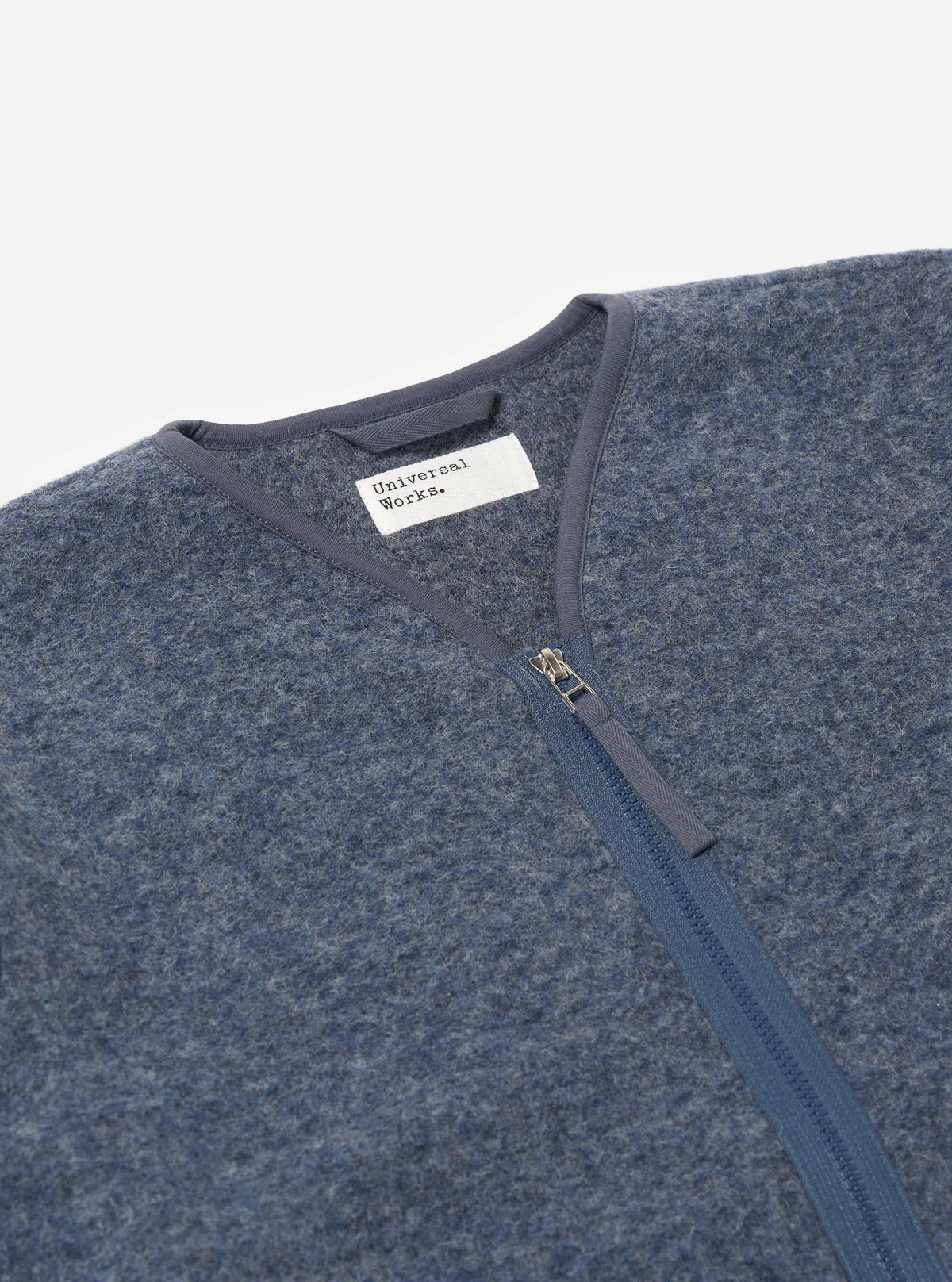 Blue fleece jacket with a zipper and 'Universal Works' label on a light gray background