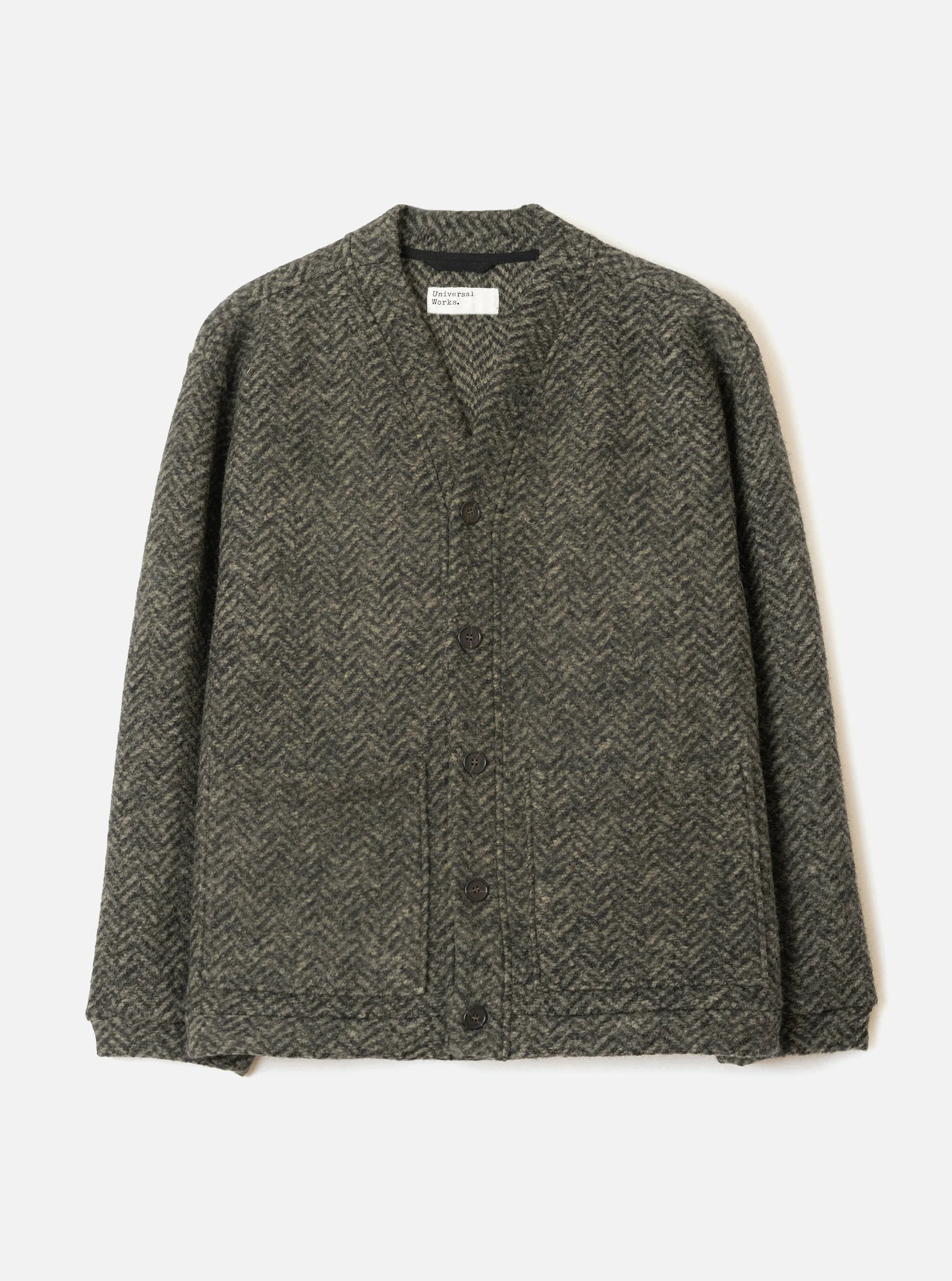 A dark green and black herringbone pattern Universal Works cardigan sweater with a button-down front, laid flat against a light off-white background.
