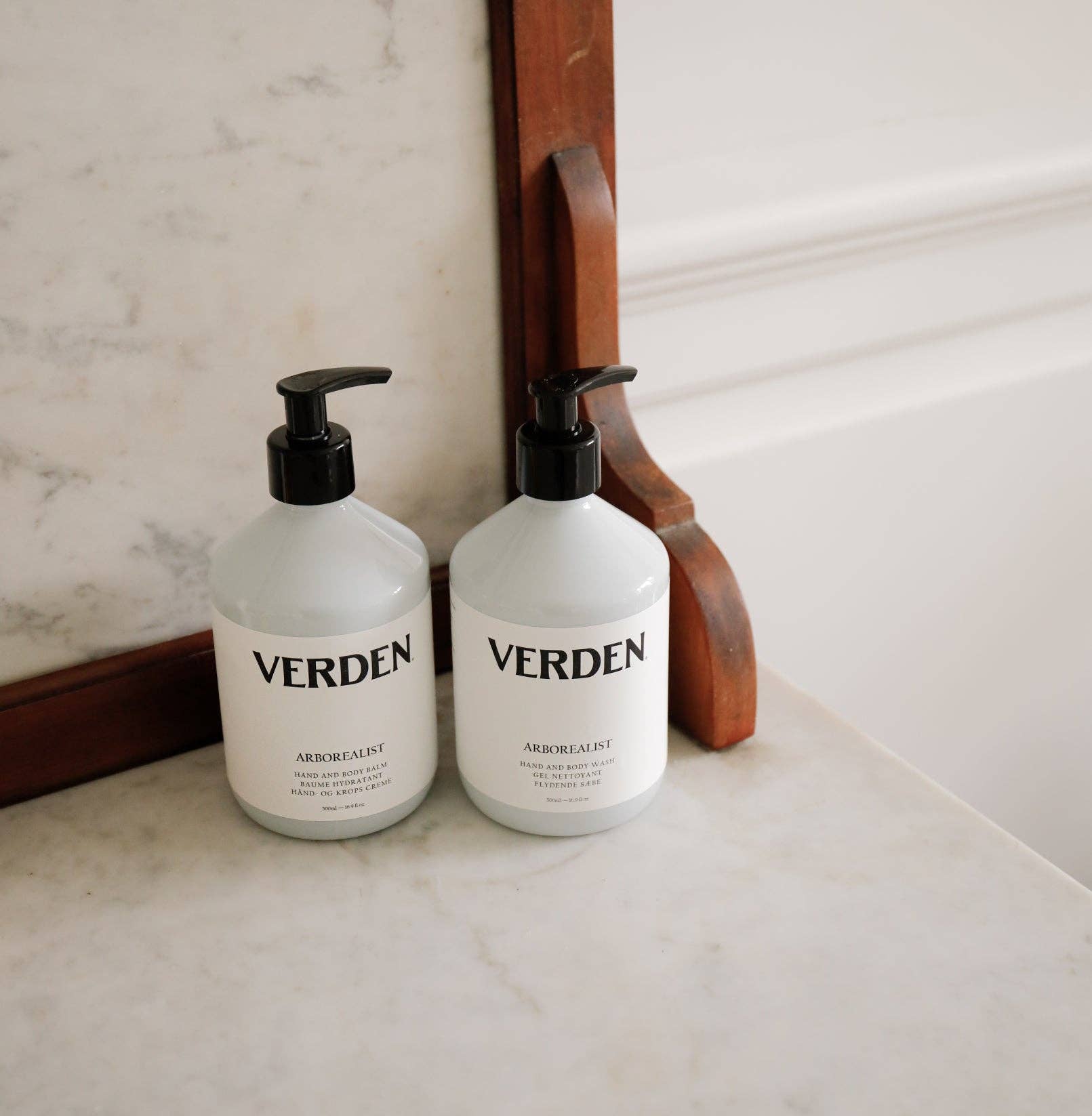 Two 'VERDEN' bottles on a marble surface with a wooden frame in the background.