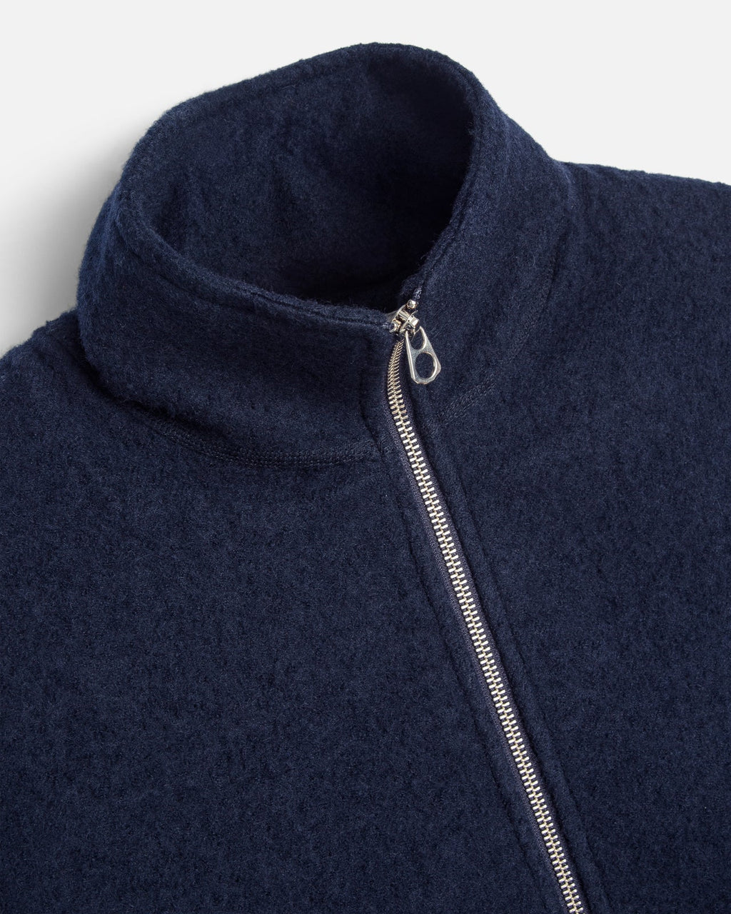 Close-up of a navy blue fleece jacket with a high ribbed collar and a silver metal zipper.