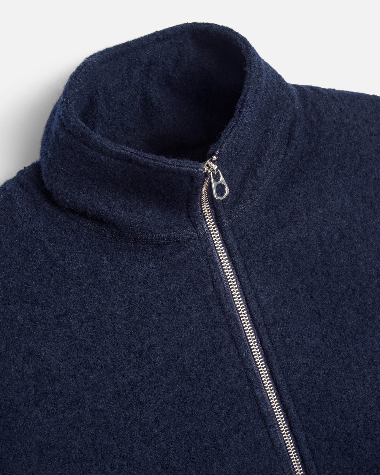Close-up of a navy blue fleece jacket with a high ribbed collar and a silver metal zipper.