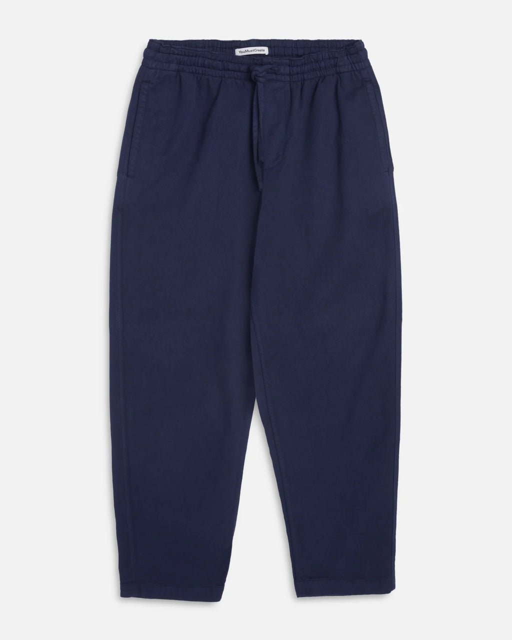 A pair of navy blue You Must Create Alva Skate trousers with an elastic waistband and drawstring, shown flat against a light grey background.