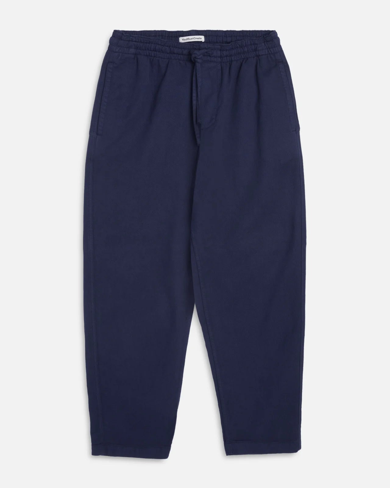 A pair of navy blue You Must Create Alva Skate trousers with an elastic waistband and drawstring, shown flat against a light grey background.