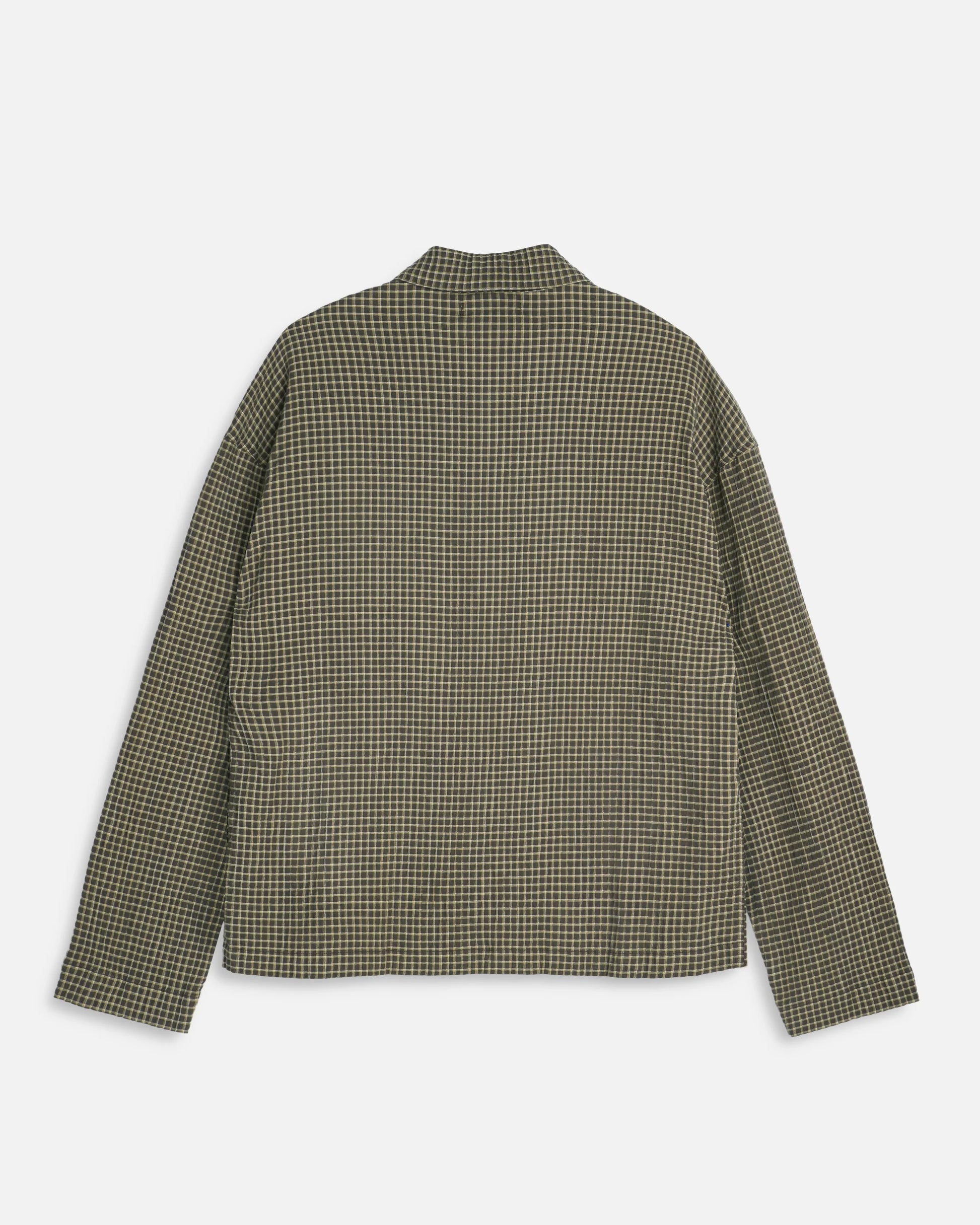 A long-sleeve YMC PJ button-up over shirt with a small-scale green and beige checkered pattern, shown from the back on a light gray background.