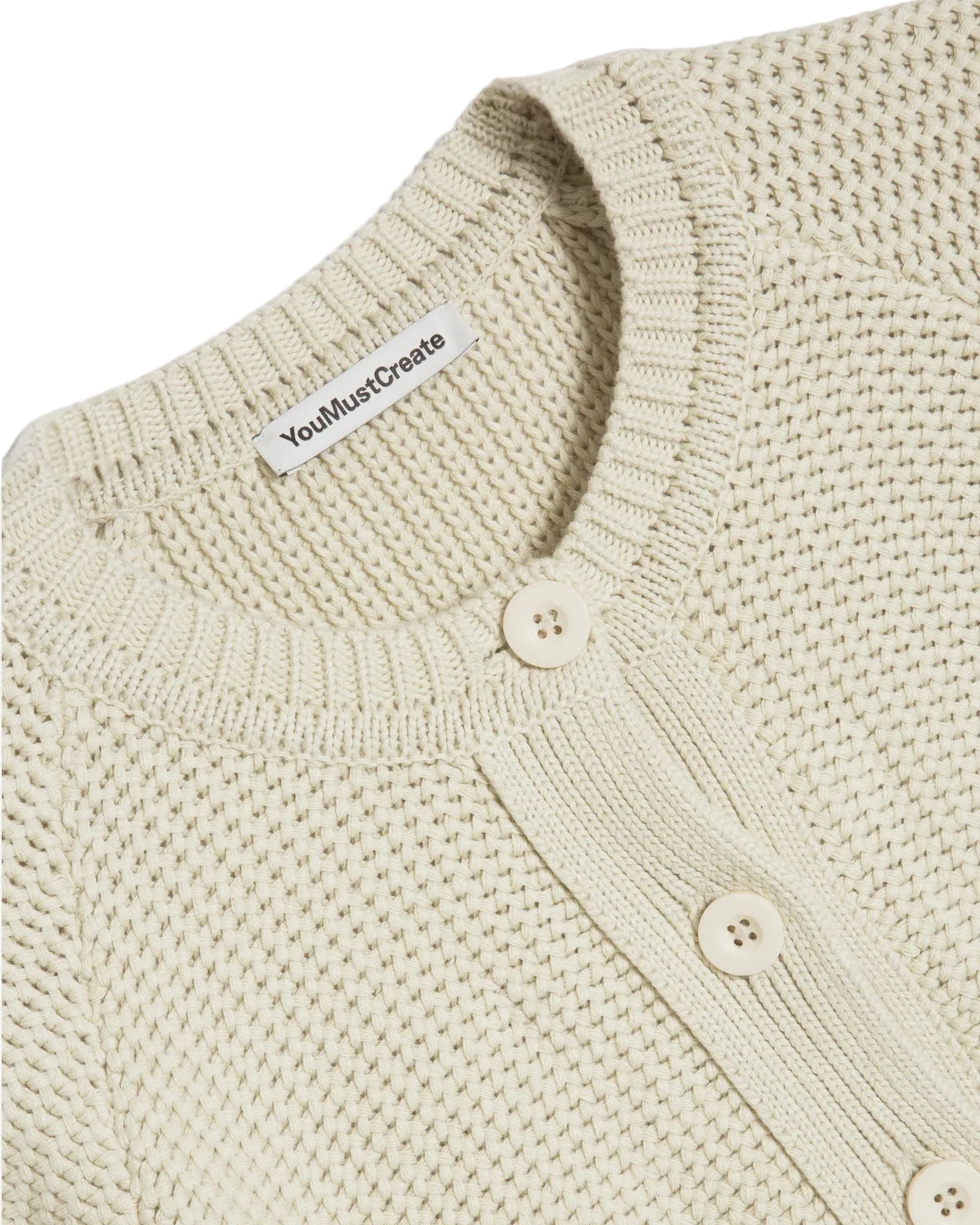 Close-up of a light yellow knitted cardigan with button details on a white background