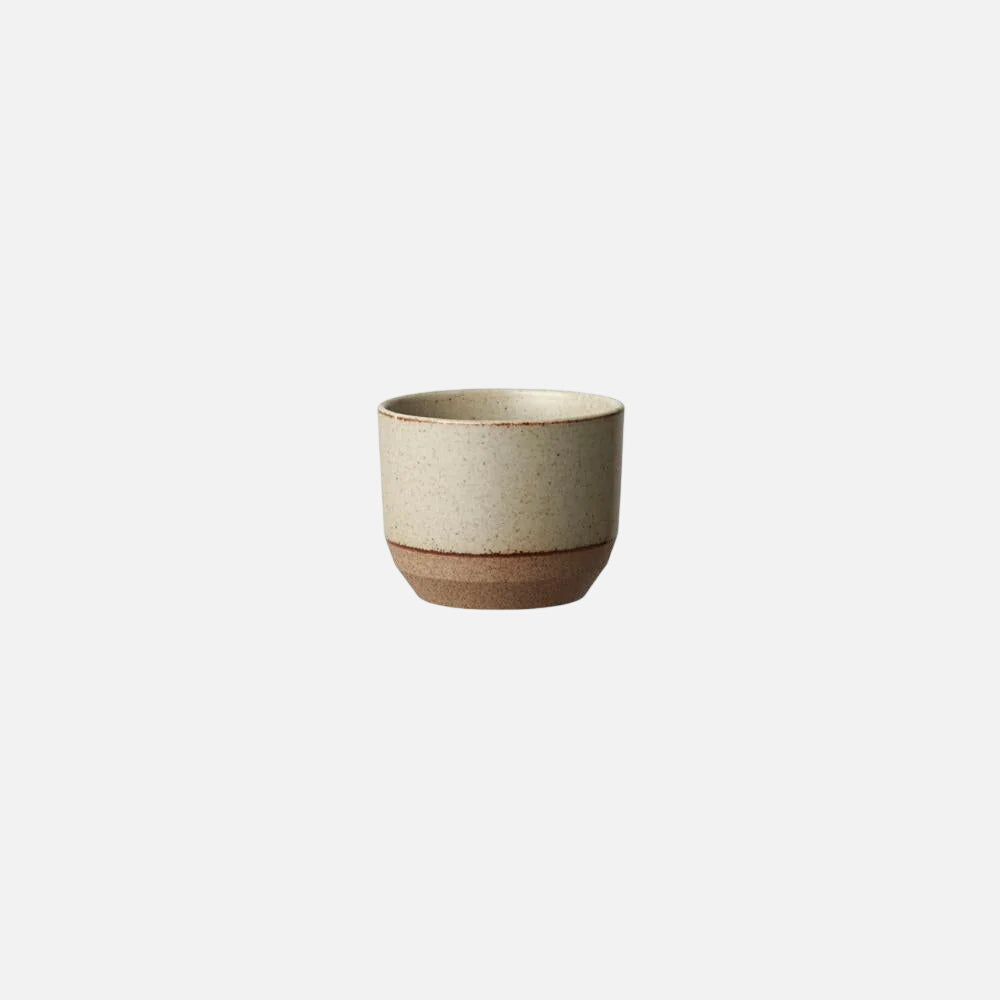 A small ceramic cup with a speckled beige upper body and a contrasting brown base, centered on a plain white background.